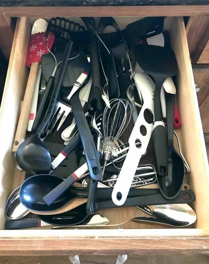 Kitchen drawer before organization with all utensils cluttered together.
