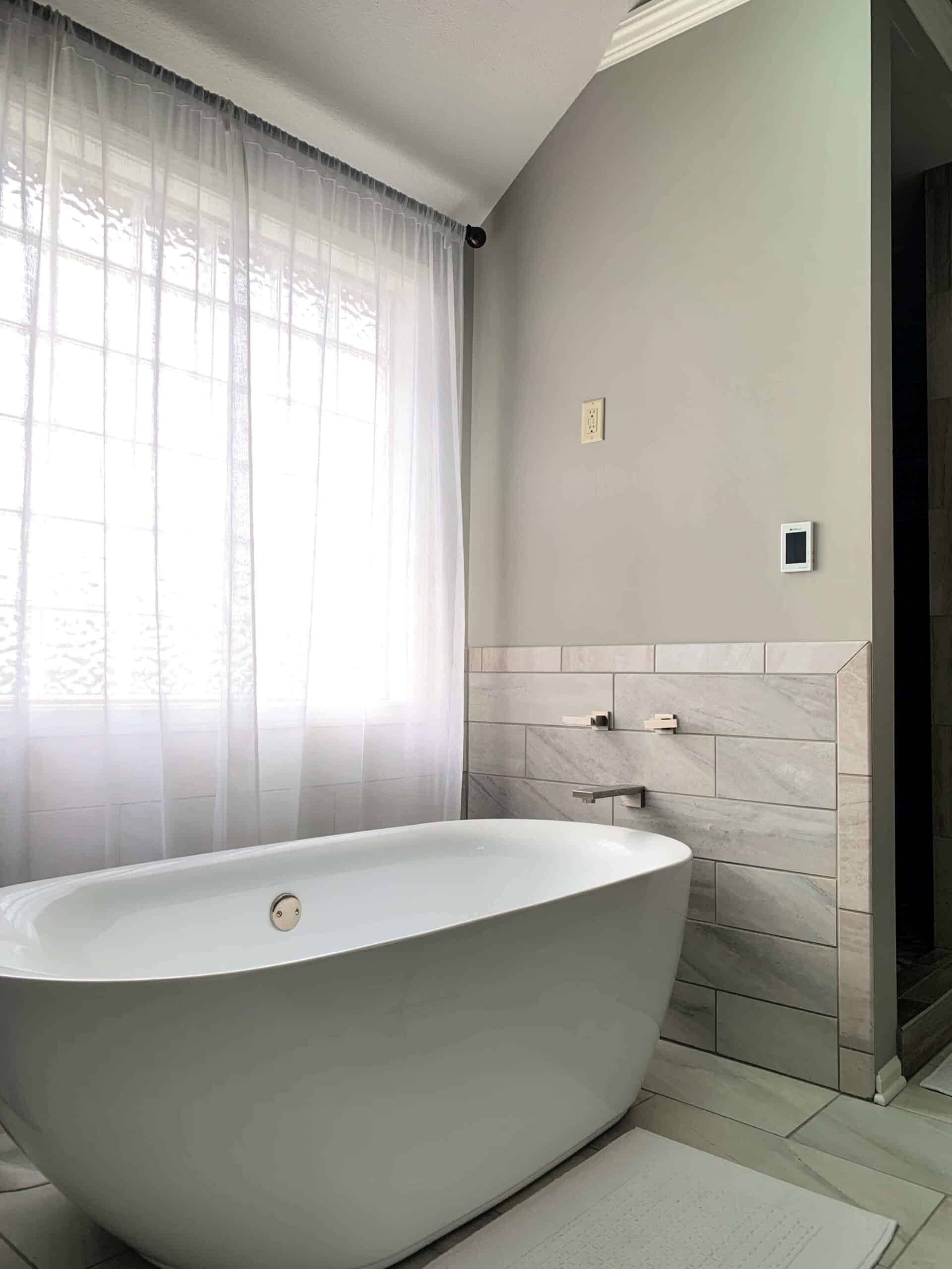 Bathroom with mindful gray paint on walls and white stand alone tub.
