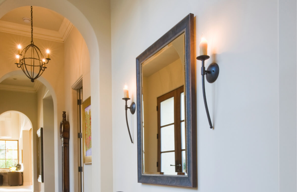 Large wall mirror with candle sconces flanking mirror.