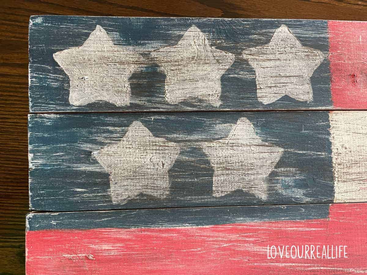 Painting the blue portion of flag when using star stencils to paint white on wooden flag of Unites States.