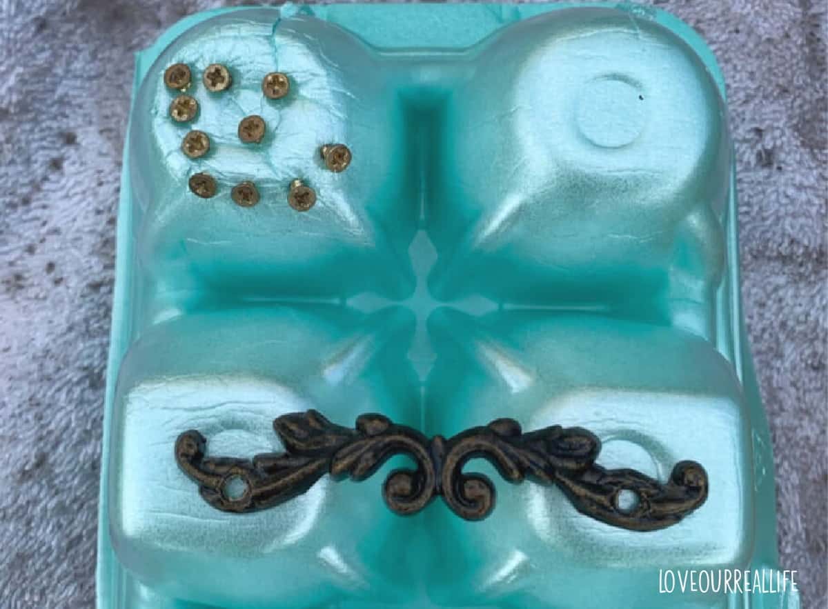 Using egg carton to push hardware of jewelry box into during spray painting.