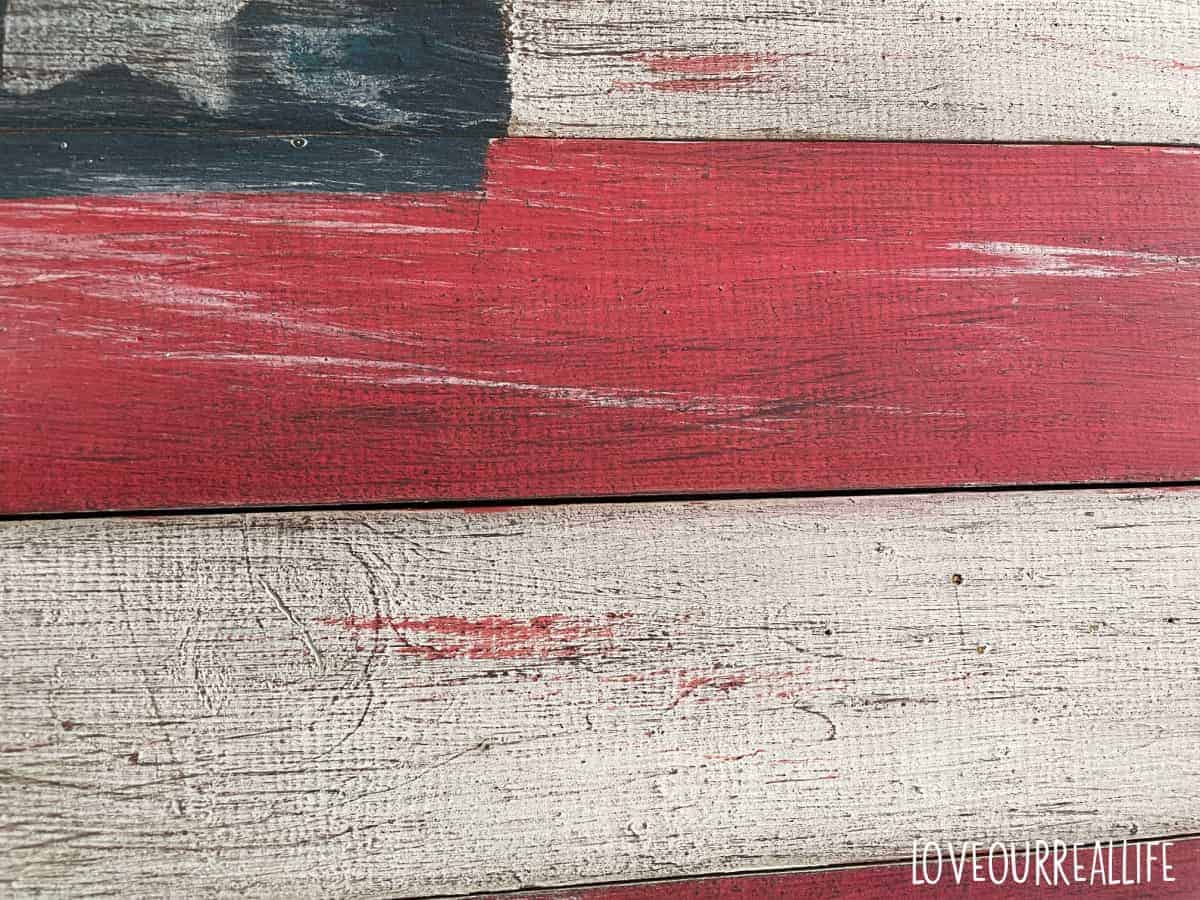 Using wood stain to dry brush on wooden USA sign for rustic look.