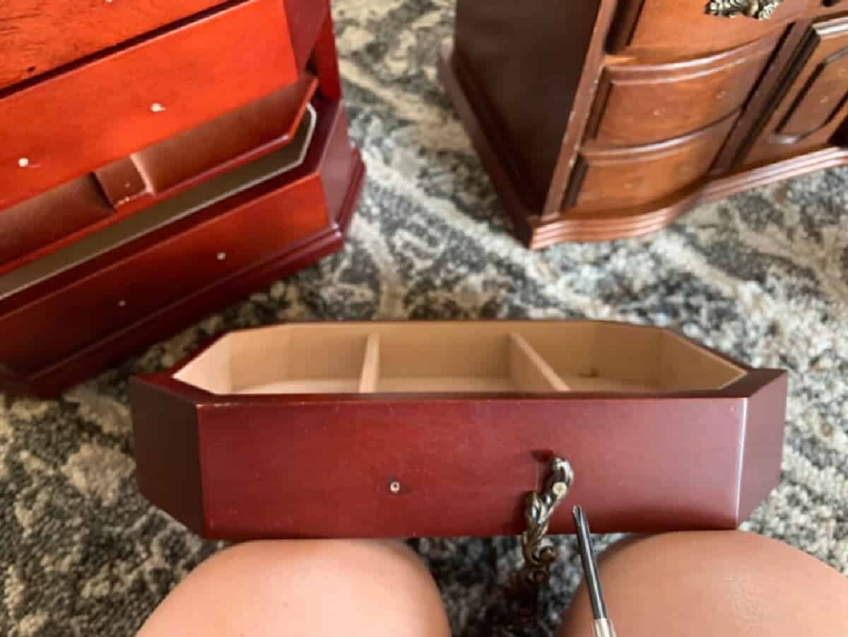 Using small screwdriver to remove hardware from jewelry box.