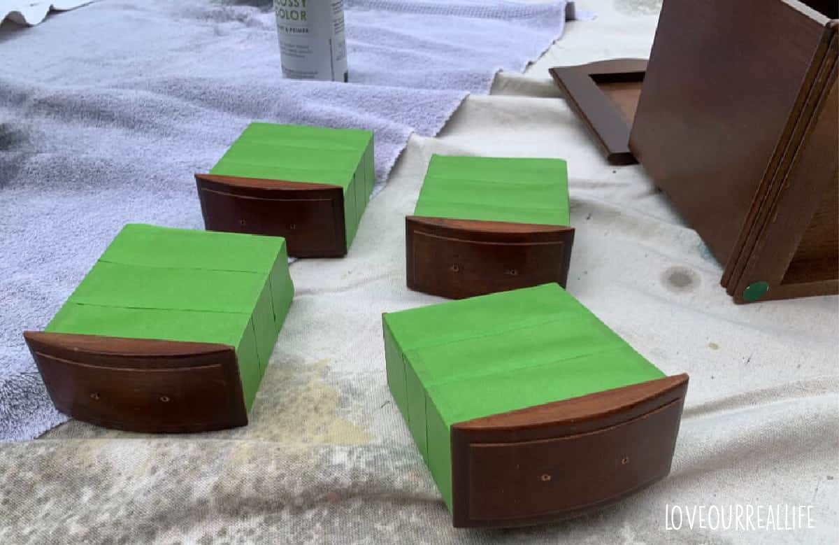 Preparing jewelry box drawers prior to painting by taping off inside of drawers.
