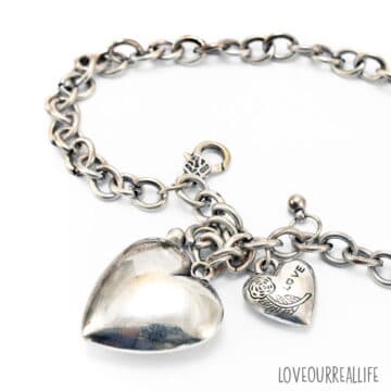 Close up of tarnished silver heart bracelet on white background.