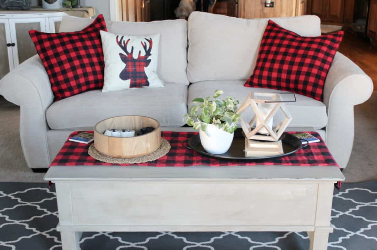 Pottery Barn cream couch with buffalo plaid pillows beside coffee table with matching table runner.