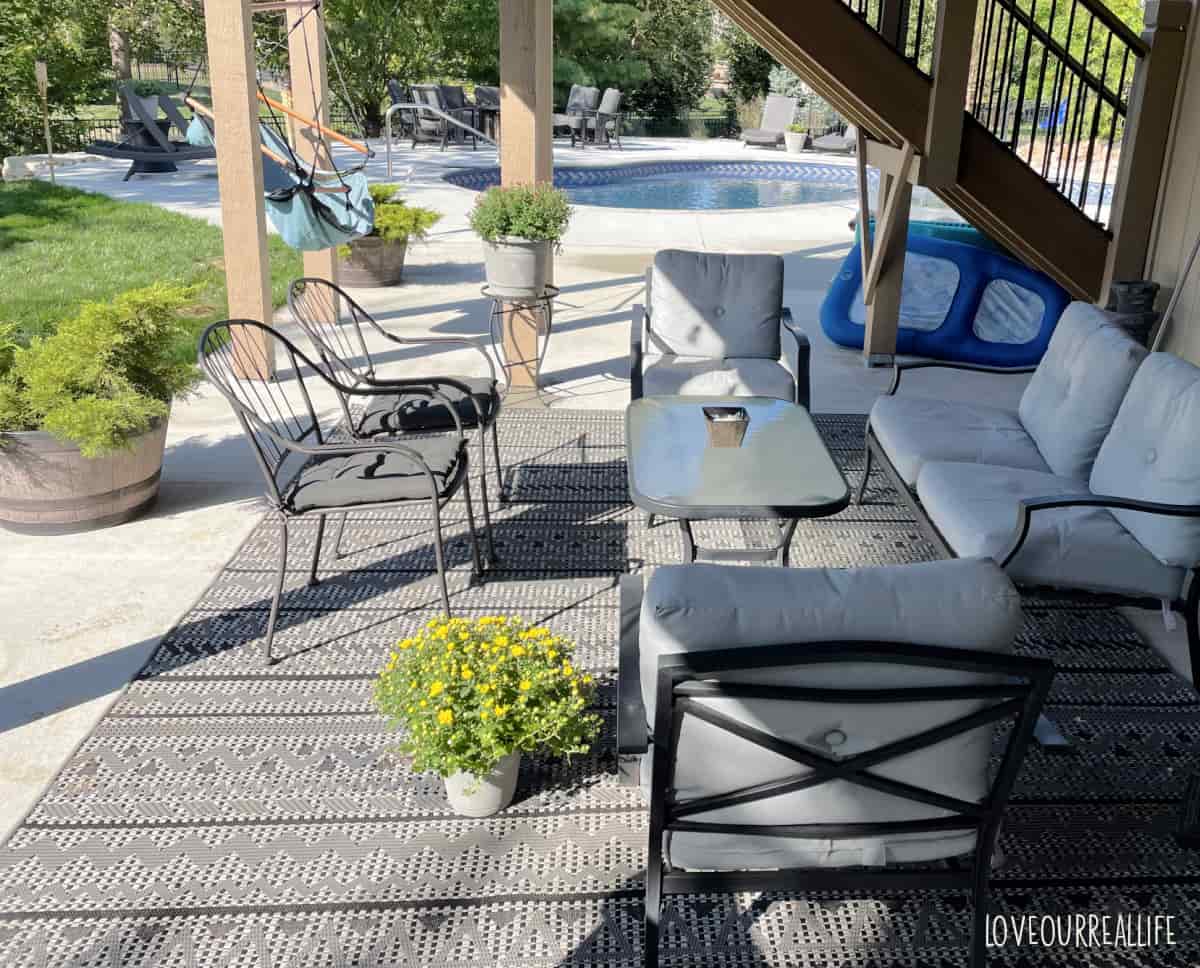 Concrete patio with rug and gray patio furniture.
