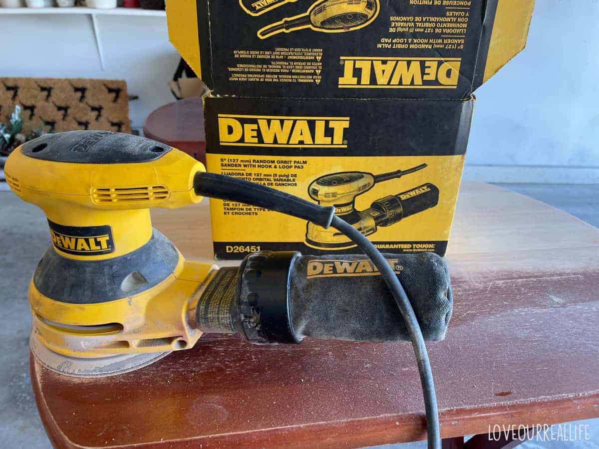 Dewalt Hand Sander removing red-brown stain from table top.