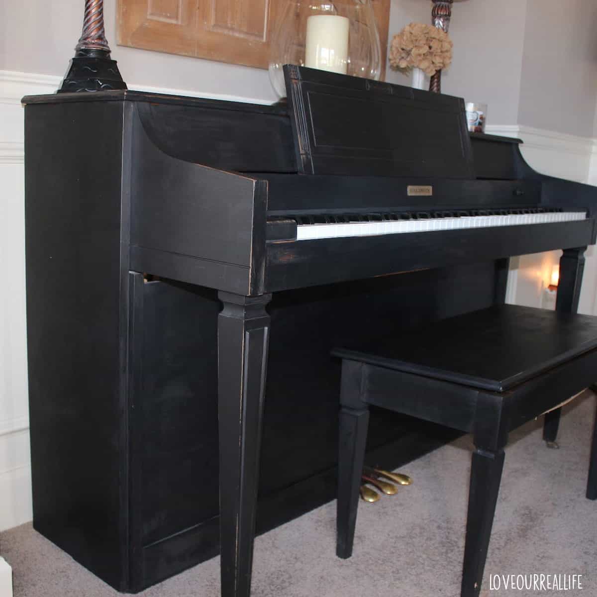 Black piano with bench side view.