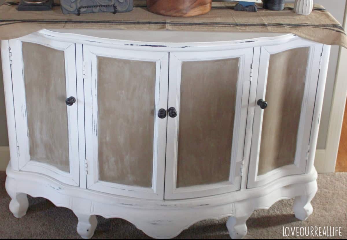 White and tan painted cabinet with distressed edges.
