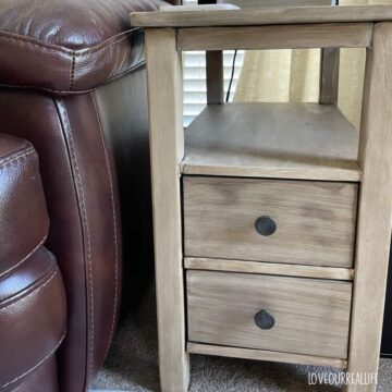 Side table with furniture glaze in brown beside leather coach.