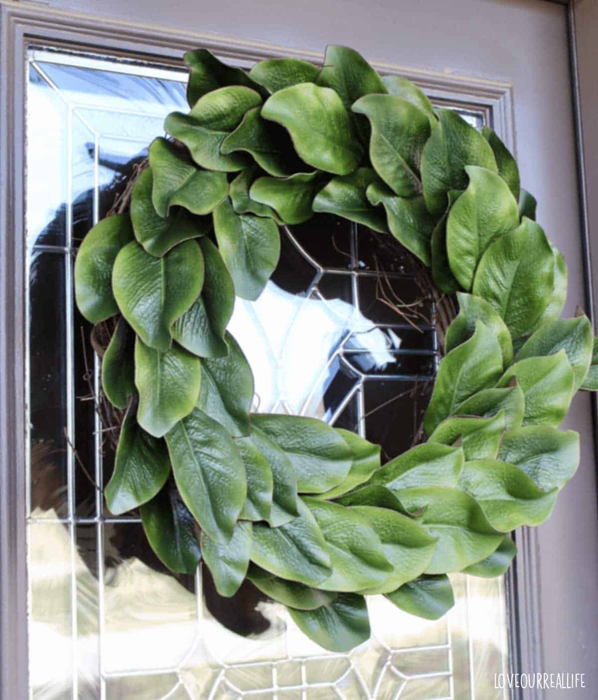 DIY magnolia wreath hanging on front door by command hook.