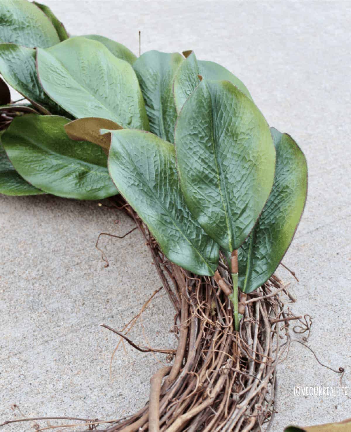 Placing floral stems around grapevine wreath to fill it in.