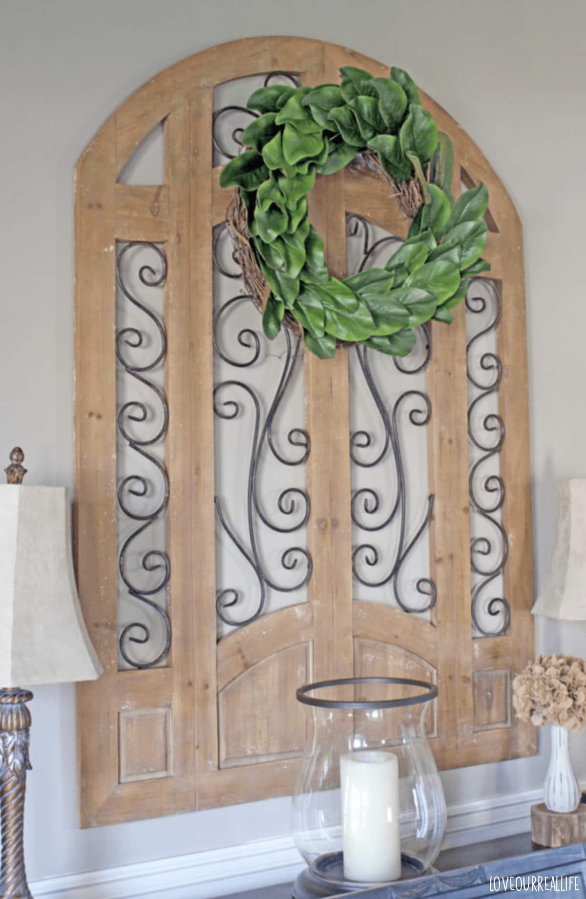 Magnolia wreath hanging on wall above black piano.