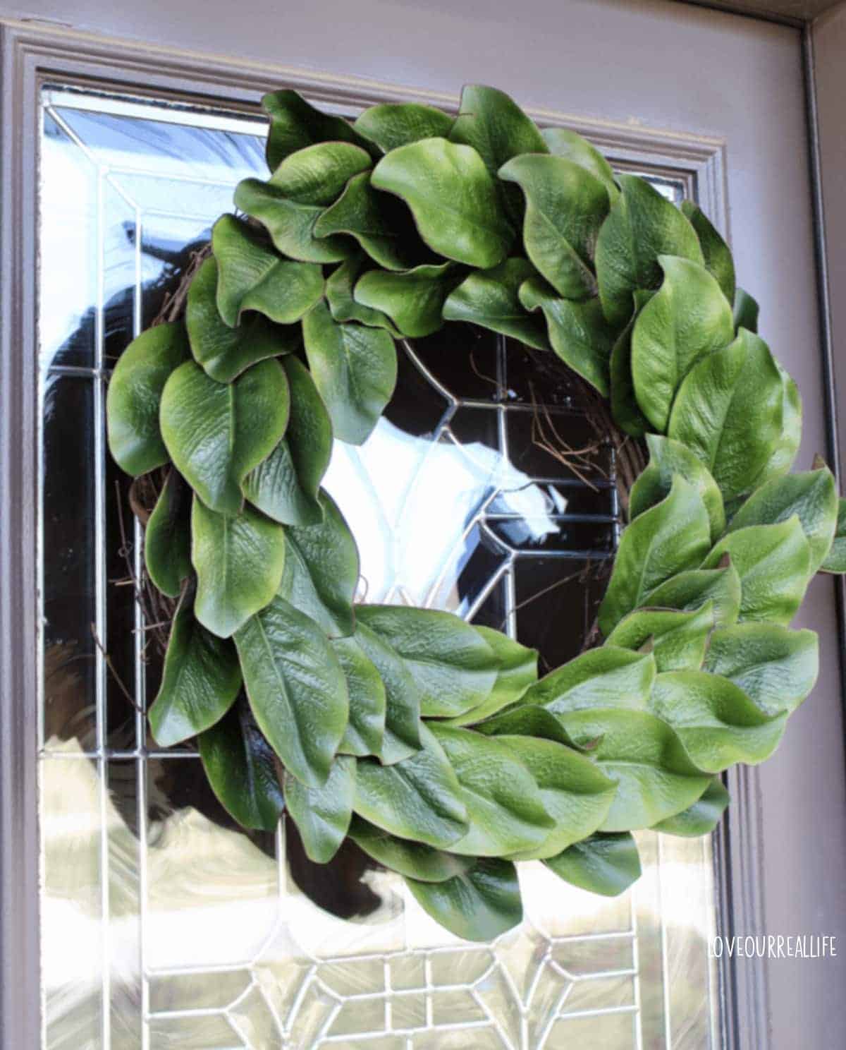 Green diy magnolia wreath hanging on front door.
