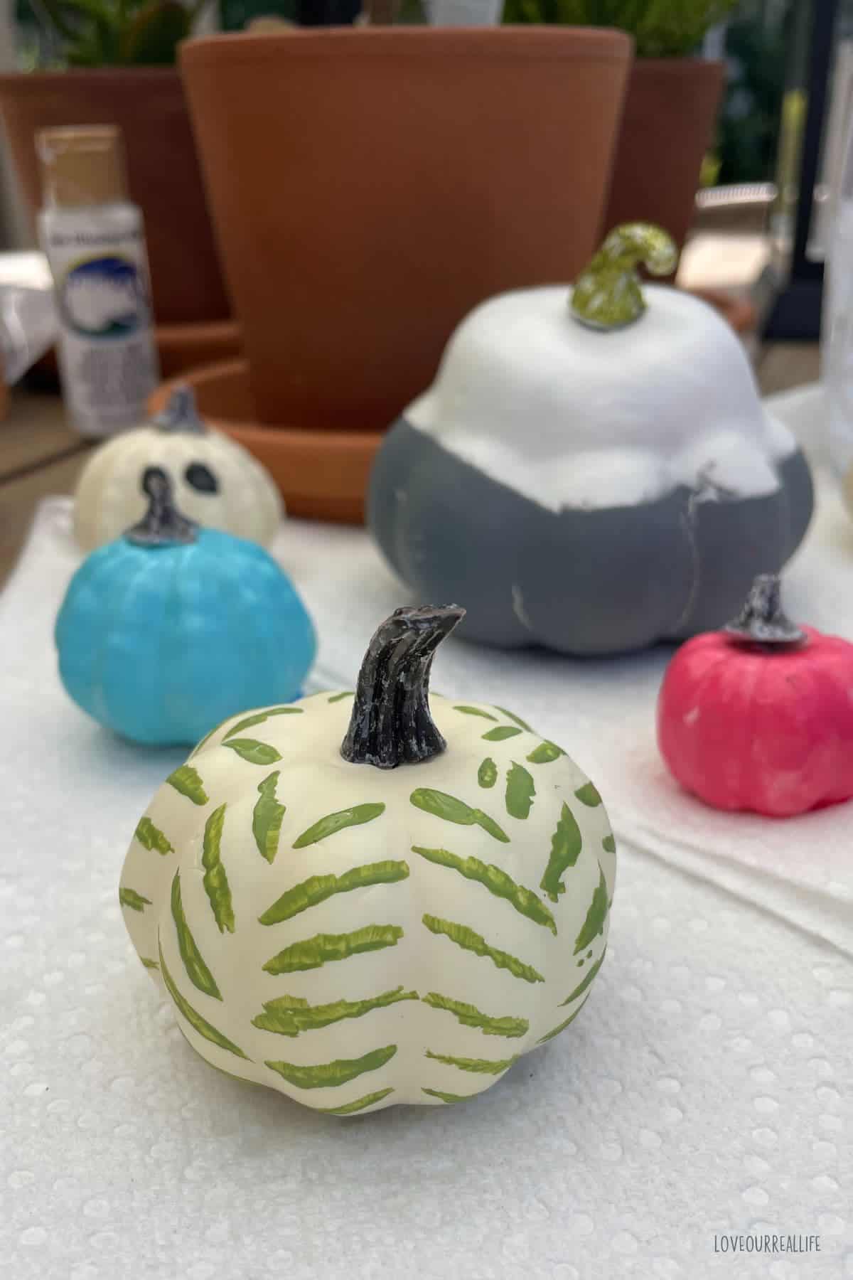 Plastic pumpkin painted with green acrylic paint in herringbone pattern.