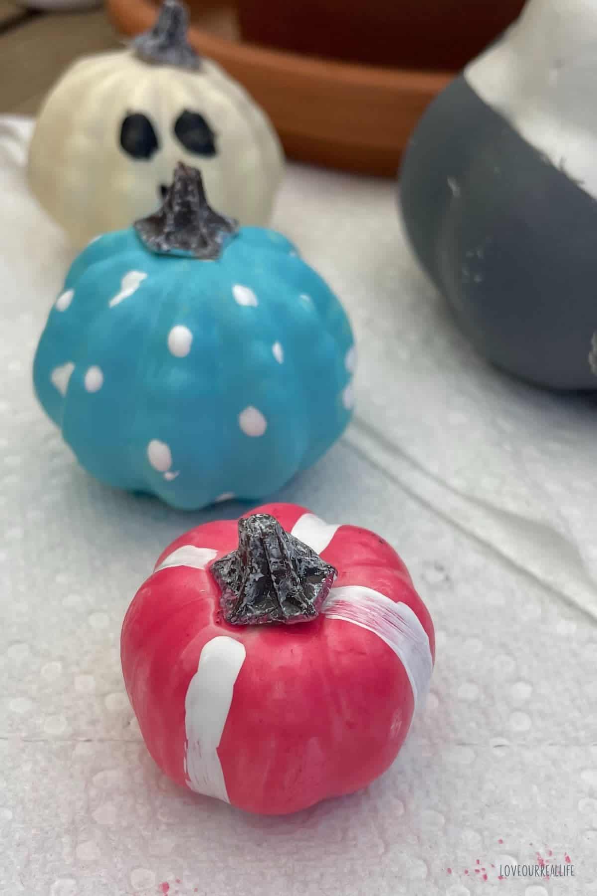 Pink pumpkin with white stripes and blue pumpkin with white polka dots.