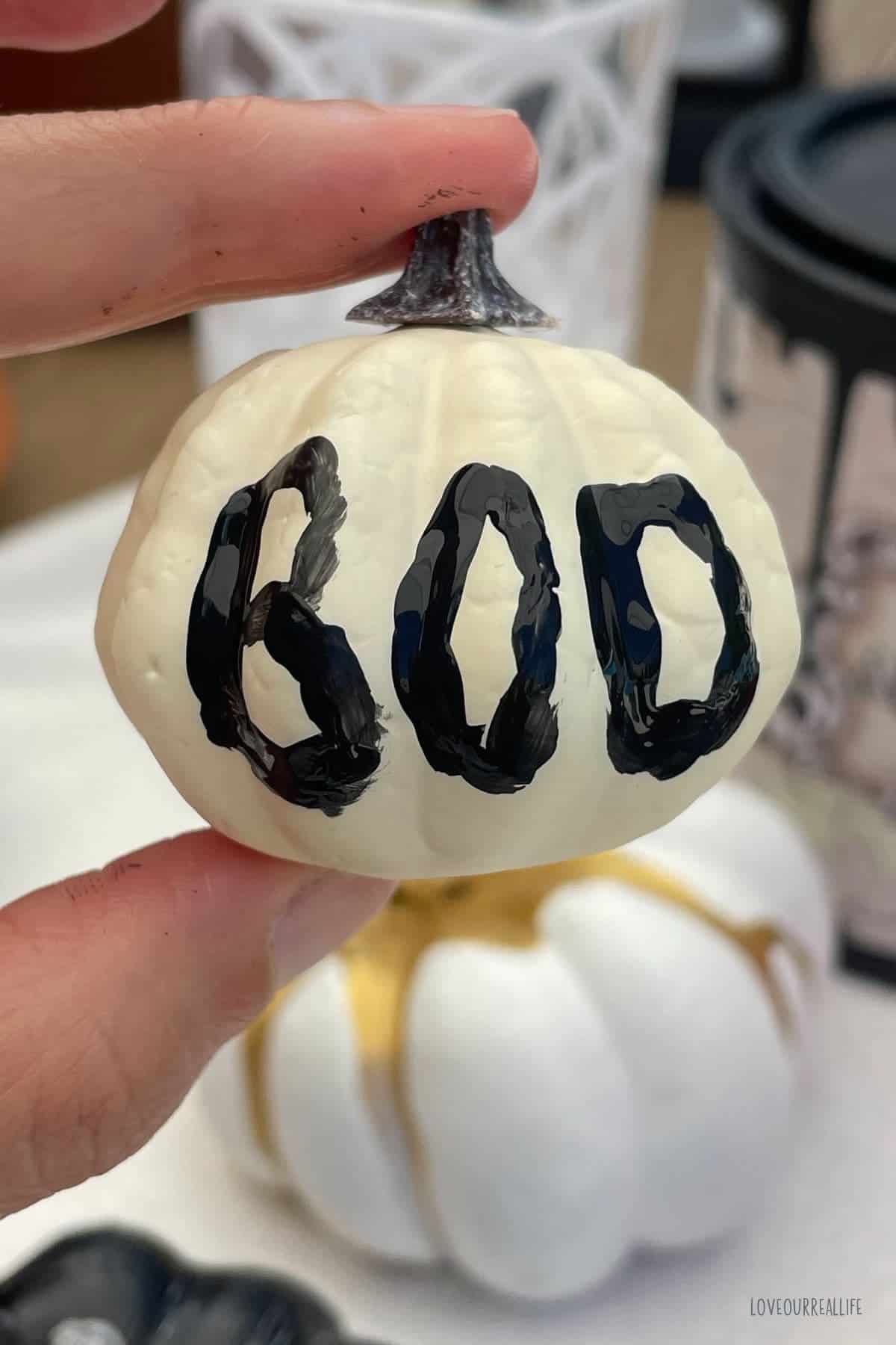 Pumpkin with word "boo" painted on it in black paint.