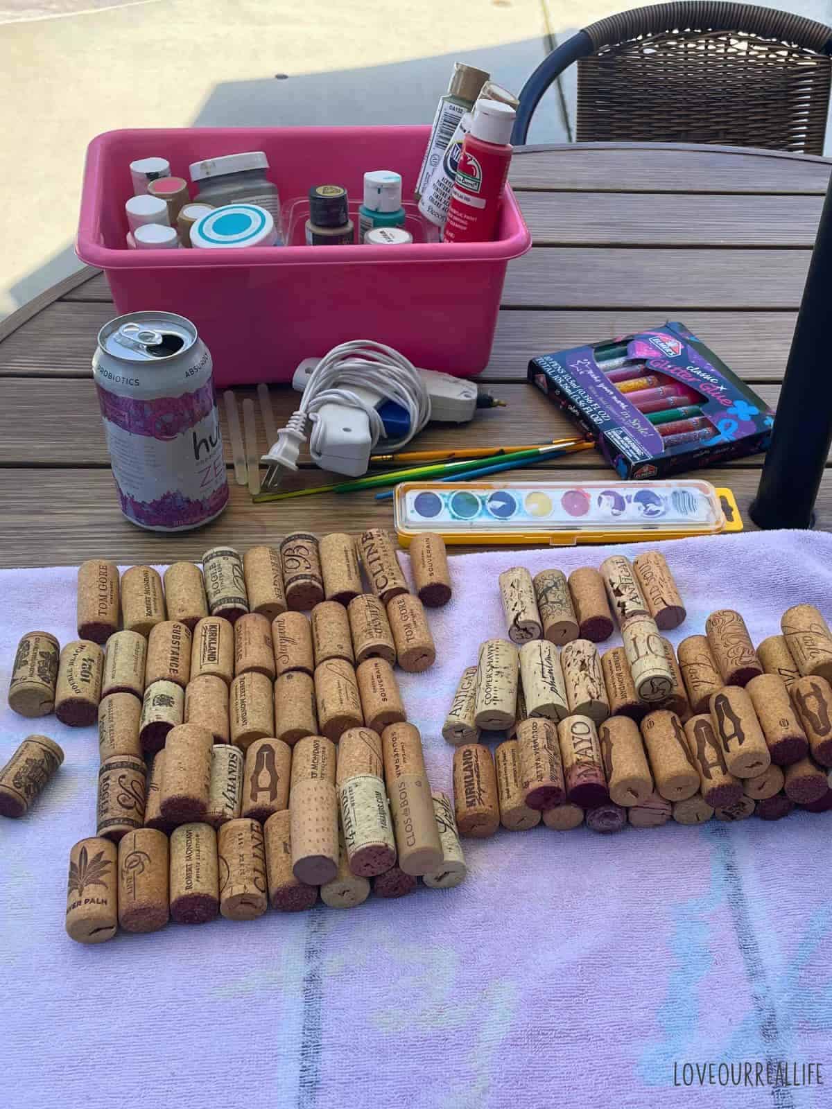 Supplies for wine cork santa hat: corks, paint, paint brushes, hot glue gun.