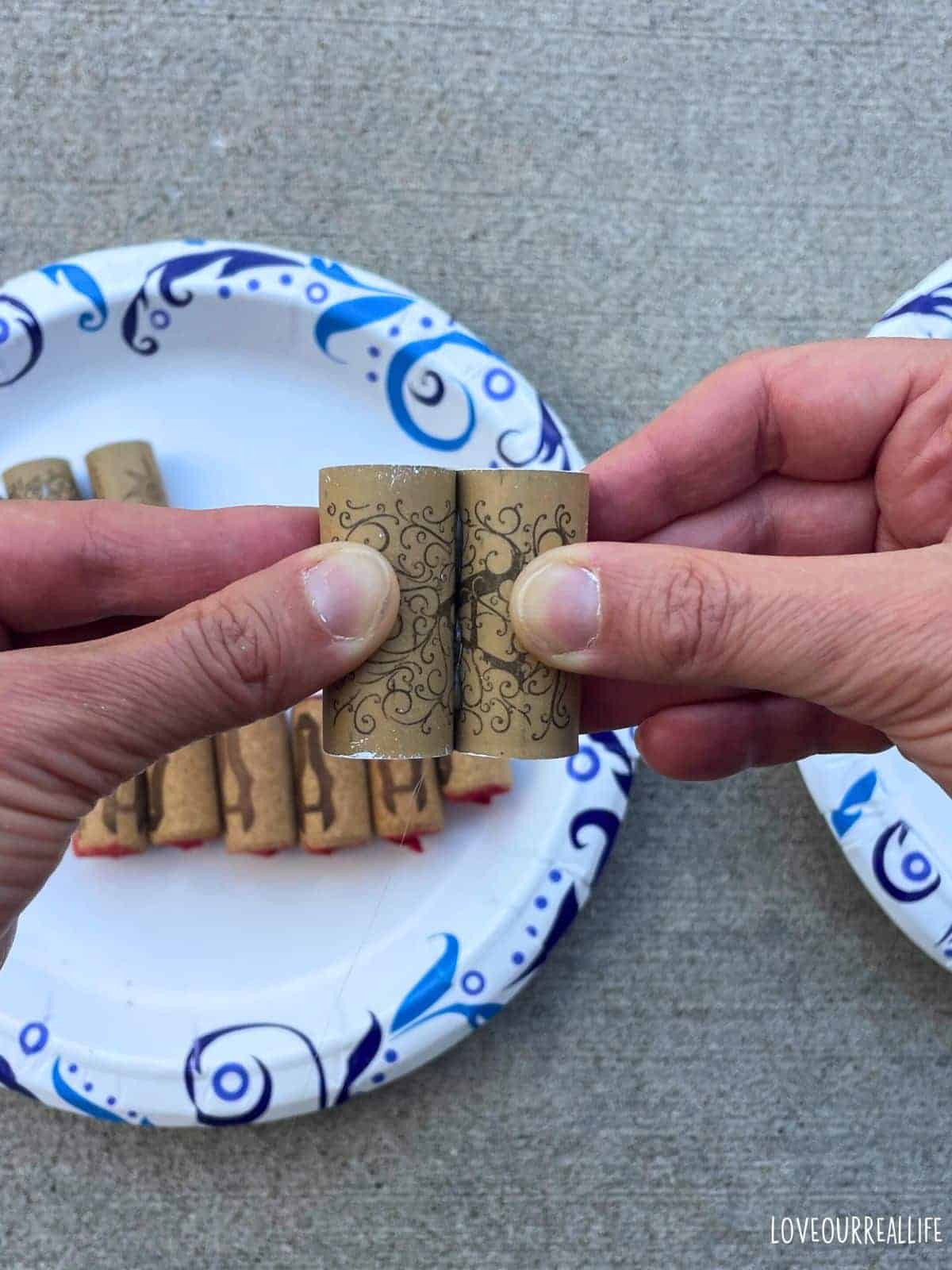 Woman holding two wine corks so hot glue will dry.