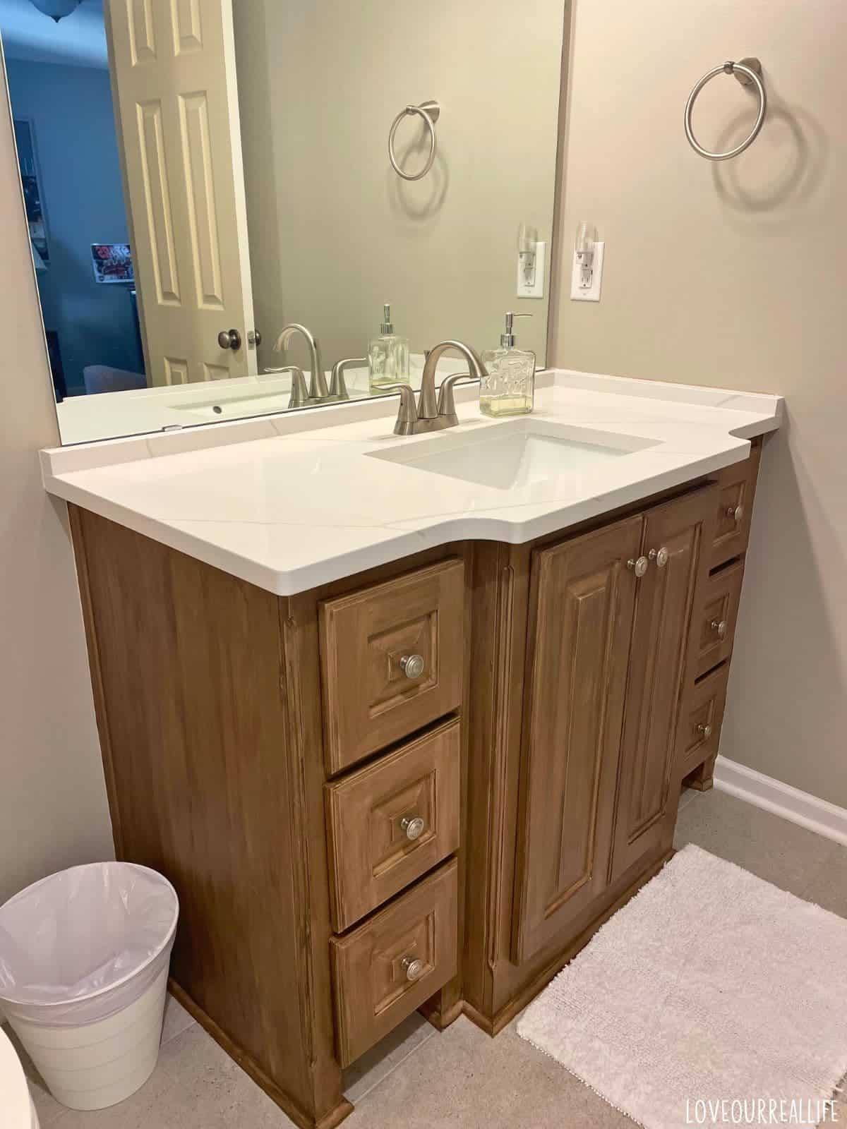 Faux wood grain paint and white quartz countertops for bathroom vanity.